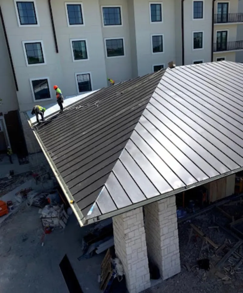 Crew installing standing seam metal roof panels on a commercial project in Bangor